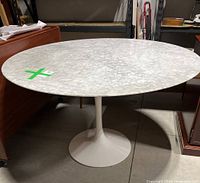Full view of round marble table top on white pedestal base