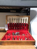 View of the full open wooden canteen box showing the flatware inside on red and white lining