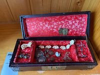 Open wooden jewelry box displaying various sterling silver earrings, rings, and chains on red floral fabric lining. Hinges appear broken.