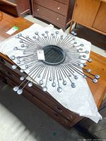 Sunburst styled mirror with a round central mirror and outward radiating rods tipped with clear crystal embellishments laid on a table.