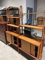 Front view of the two-piece teak shelving unit showing four shelves and bottom cabinets
