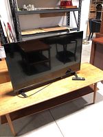 Front view of the 39-inch Insignia TV showing the screen and angled legs on a wooden table.