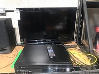 Front view of Panasonic 26-inch TV with Panasonic DVD/VHS player and remote controls on table.