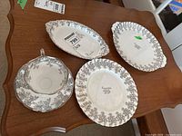 Photo showing the full set: anniversary plate, two oval serving dishes, cup and saucer on wooden table