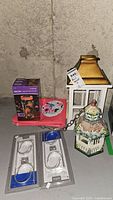 Photo of all lot items together showing bird houses, pole hangers, solar jar string light in box, and wall art.