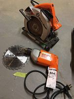 Photo of Black & Decker circular saw and electric drill with attached blade on floor showing both tools and cords.