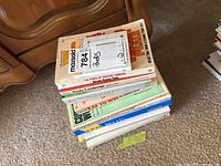 Stack of health and wellness books on carpeted floor, close up of spine titles and MaxSold tag visible.