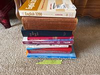 Stack of 7 books showing spines and some front covers, arranged on carpet, depicting titles related to English and communication studies.