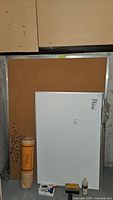 Whiteboard, bulletin board, markers, erasers, cleaner, and paper pad arranged in basement setting