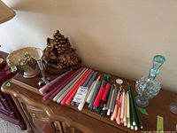 Wide view of the assortment including candles, candlestick, grape motif wall sconce, bowl, and glass bottle on a wood dresser