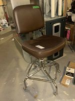 Side and front angle of brown vinyl and cloth swivel office chair on chrome casters