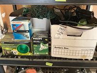 Photo showing two boxes on a shelf: one with Christmas lights in green wiring and assorted bulbs in boxes labeled Sylvania and Philips