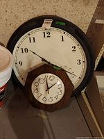 Pair of two plastic framed clocks, large clock with humidity and temperature gauges, smaller octagonal Bulova quartz clock in brown frame.