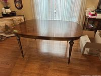 Laminate dining table with dark brown finish, viewed from an angle showing legs and top surface