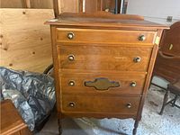 Front view of vintage wood dresser showing four drawers and decorative handles
