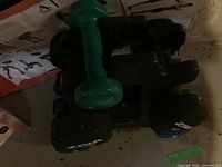 Dumbbell weight rack holding various dumbbells including a green 2 lb dumbbell and several black dumbbells