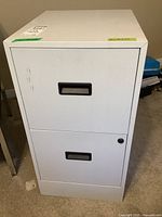 Front view of white metal two-drawer filing cabinet showing recessed handles and lock on the bottom drawer.