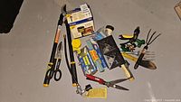 Full overview of garden tools laid out on floor showing various items including loppers, scissors, hose connectors, and other garden accessories.
