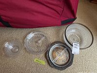 Five glass serving dishes on carpet, including a large bowl, divided dishes, and silver-plated tray.