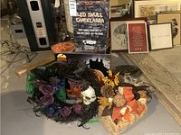 Photo showing a boxed LED skull candelabra, a decorative pumpkin with autumn ribbons and berries, black wreath with purple roses and feathers, orange Halloween plate, and various other Halloween decorations.