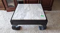 Front view of the square marble top side table showing the white marble surface with grey veining and dark wood base with carved legs.