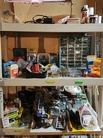 Photo showing shelves with hand drill, numerous small organized drawers of screws and nails, files, plane, and other assorted hardware tools and materials below and on shelves.
