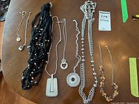 Seven assorted costume jewelry necklaces arranged on table showing variety in style and materials.