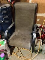 Full view of the outdoor patio chair with woven vinyl seating and black metal frame showing condition and surroundings.