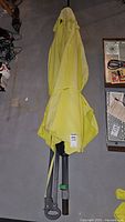 Full view of the folded yellow patio umbrella showing the canopy and pole.