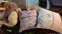 Photo shows three plush toys, two decorative pillows, and part of the book 'Amelia's Loose Parts'.