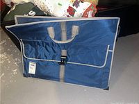 Blue vinyl portfolio bag closed, front view showing buckle closure and carrying handles.