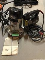 Photo showing Sears Craftsman router with power cord and instruction manual on a surface alongside a Stanley sabre saw.