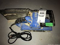 Mastercraft electric belt sander with black dust bag, shown from top view with power cord coiled beside it.