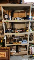 Front view of plastic shelving unit filled with various tools and items (contents not included in sale). Clearly shows size and condition of shelving unit.