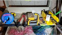 Complete set of tools arranged on a shelf showing all items including cannister auger, bolt cutters, hacksaw, bottle cutter kit, level, tubing cutter, and measuring squares.