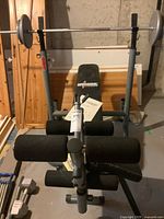 Full view of Universal B-1002B weight training bench with barbell, weights, padded rollers and manual placed on bench