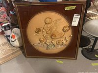 Front view of framed dried flower arrangement with gold trimmed square frame and circular matte border.