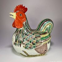 Side view of ceramic rooster serving dish showing colorful feather pattern and red comb