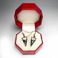 Pair of vintage Alpaca silver and mother of pearl triangle dangle earrings displayed in a red octagonal box with white cushioned interior.