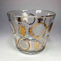 Front view of vintage clear glass ice bucket decorated with etched leaves and gold leaf circles.