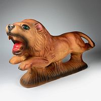 Clear angled view of the ceramic lion showing its prancing pose, paint details, and green sequin eyes.