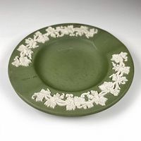Top view of circular sage green jasperware ashtray with white grape and vine relief around the rim.