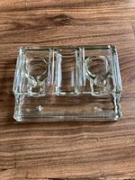 Top view of the clear glass desk accessory showing two circular ink well holders and a central pen holder section with a ridged edge.