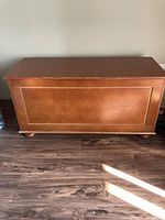 Front exterior view of the wooden blanket box showing the medium brown finish and four rounded feet.