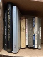 Box containing eight books with visible titles including The New Canadian World Atlas, The Music of Man, and others.