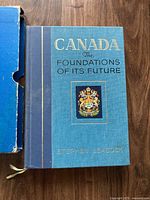 Front view of hardcover book in blue cover with gold text and Canadian coat of arms.