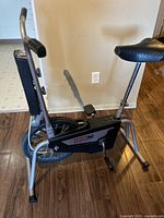 Side view of silver CCM exercise bike showing frame, cushioned seat, and pedals.