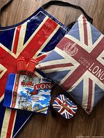 Overview of all items in the lot including Union Jack cushion, apron, salt and pepper shakers, small tin, and tea towel.