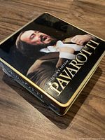 Closed metal tin box with Pavarotti image and title on lid