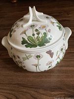 Top and side view of covered ceramic casserole displaying botanical pattern with daisies, dragonflies, and butterflies.